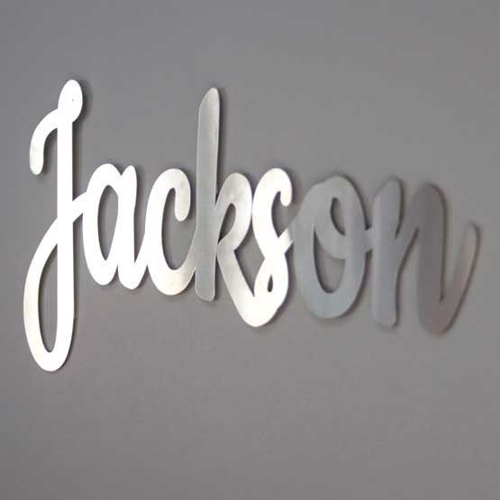 Custom Cut Stainless Steel Metal Sign Featuring Cursive Style Jackson Name Hanging On A Gray Living Room Wall