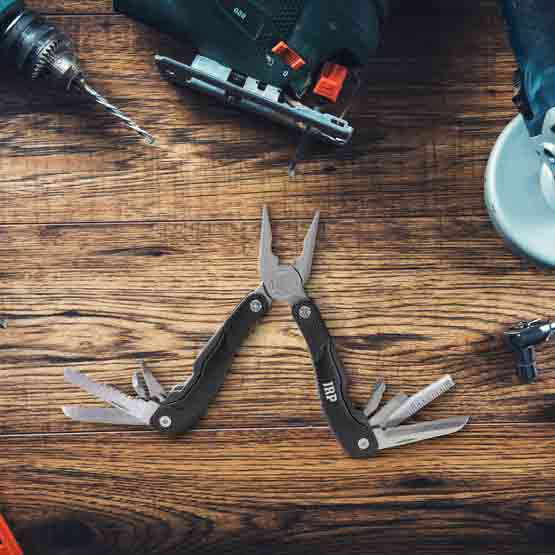 Custom Black Stainless Steel Multi Tool Laser Engraved With Initials In Open Position On A Wood Table With Power Tools
