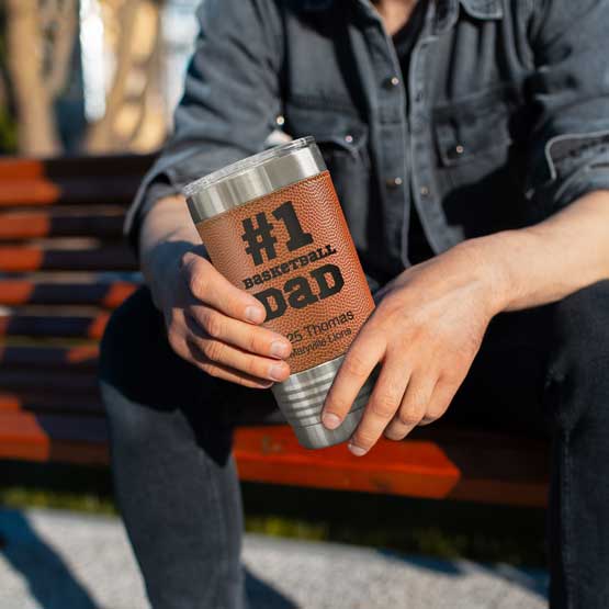 Man On Park Bench Holding Faux Leather Wrapped Coffee Tumbler With Basketball Theme And Number One Baseball Dad Message