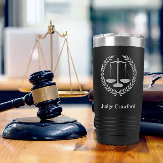 Black 20 Ounce Tumbler Engraved With Justice Scales Art And Judge Crawford Text On Office Desk With Gavel And Notepads