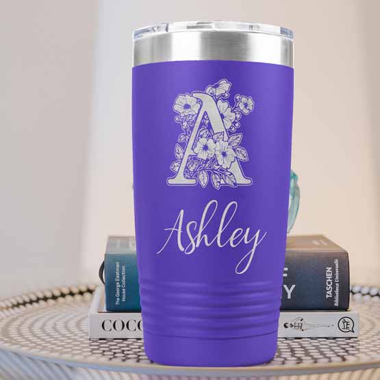 Purple Twenty Ounce Stainless Steel Coffee Tumbler Engraved With Ashley And Monogram And Flower Art On Table With Books
