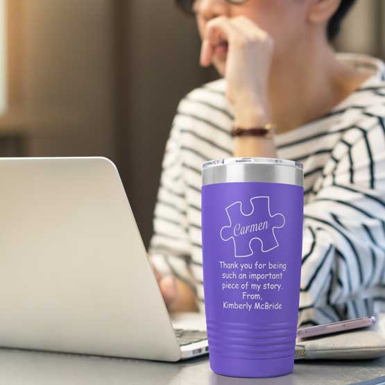 Woman At Desk With Laptop And Purple 20 Ounce Tumbler Engraved With Teacher Name Inside Puzzle Piece And Thank You Message