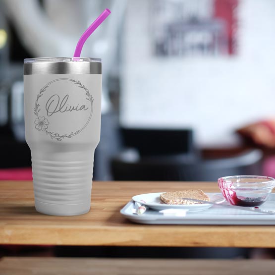 White Thirty Ounce Stainless Steel Coffee Tumbler With Straw And Engraved With Name And Flower Art On Table With Food Platter