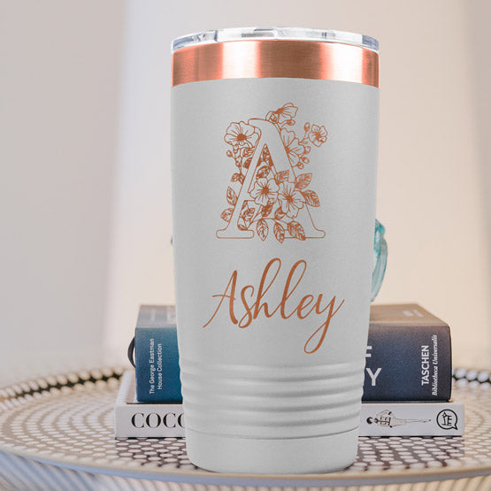 White And Rose Gold Twenty Ounce Coffee Tumbler Engraved With Ashley And Monogram And Flower Art On Table With Books