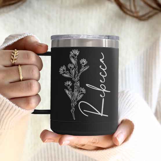 Woman Hands Holding Black Stainless Steel Coffee Tumbler Mug With Handle And Engraved With Name And Flower Art