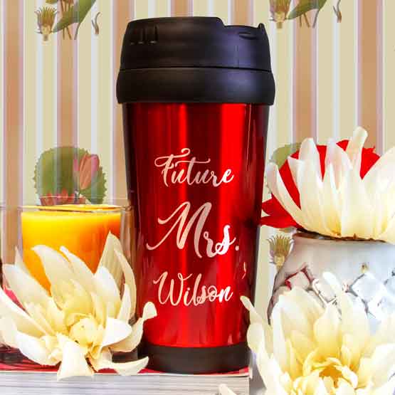 Red Travel Mug With Lid And Engraved With Future Misses Wilson Message On Shelf With Flowers And Candle And Book