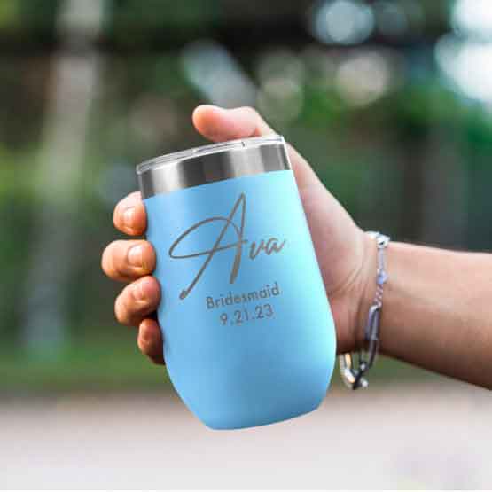 Woman Hand Outdoors Holding Custom Light Blue Stemless Wine Tumbler Engraved With Name And Date And Bridesmaid Text
