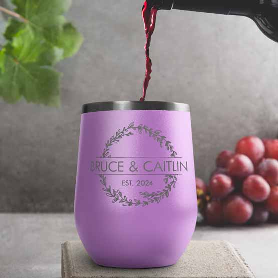 Wine Bottle Pouring Wine Into Light Purple Stemless Wine Tumbler Engraved With Names And Wheat Art On A Kitchen Counter