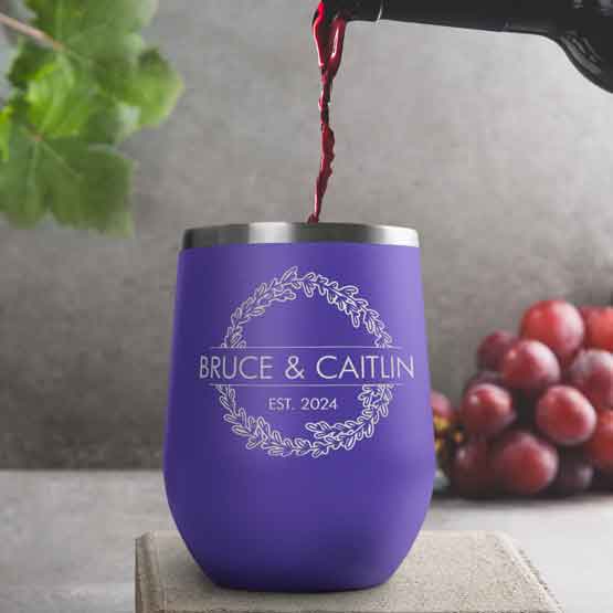 Wine Bottle Pouring Wine Into Purple Stemless Wine Tumbler Engraved With Couple Names And Wheat Art On A Kitchen Counter