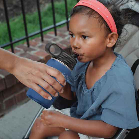 Hand Serving Blue Stainless Steel Child Water Bottle With Straw And Engraved Name To Little Girl In Stroller Outdoors