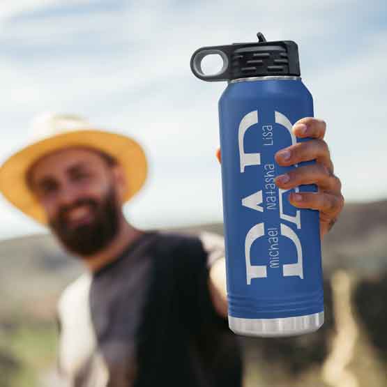 Man Hiking Outdoors And Holding Custom Blue 32 Ounce Water Bottle Engraved With Custom Children Names Inside Dad Text