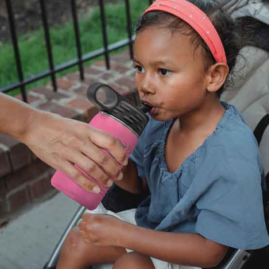 Hand Serving Pink Stainless Steel Child Water Bottle With Straw And Engraved Name To Little Girl In Stroller Outdoors