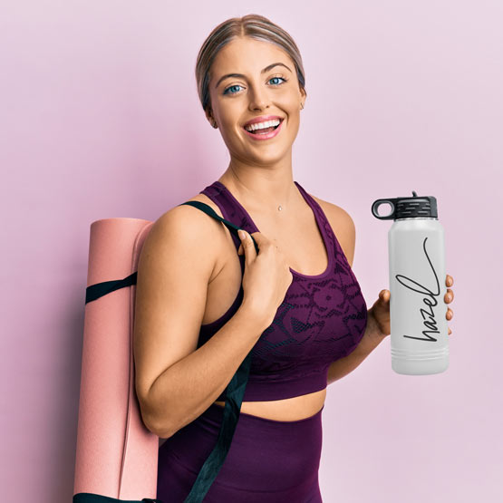Woman In Workout Clothes Carrying Yoga Mat And White And Black Thirty Two Ounce Water Bottle With Straw And Engraved Name