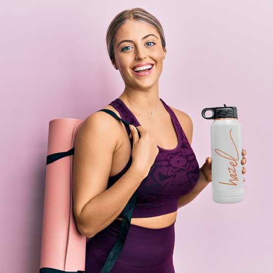 Woman In Workout Clothes Carrying Yoga Mat And White And Rose Gold Thirty Two Ounce Water Bottle With Straw And Engraved Name