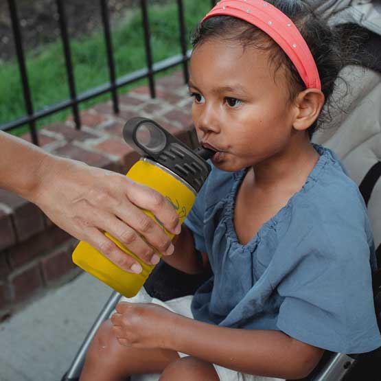 Hand Serving Yellow Stainless Steel Child Water Bottle With Straw And Engraved Name To Little Girl In Stroller Outdoors