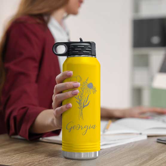 Woman At Office Desk Holding Yellow Thirty Two Ounce Water Bottle With Straw And Engraved Name And Flower Art