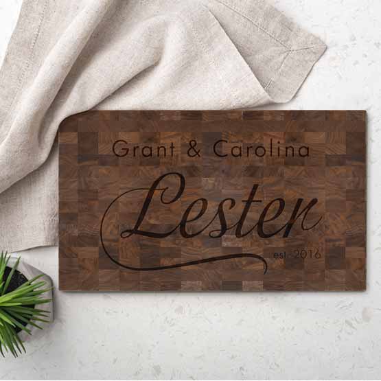 Walnut Butcher Block Cutting Board Laser Engraved With Names And Date On White Counter With Plant And Hand Towel