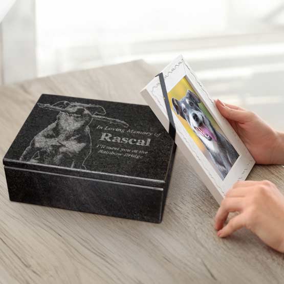 Hands Holding Picture Frame With Dog Photo On Dining Table With Granite Urn Featuring Dog Art And Memorial Message 