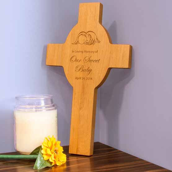 Red Alder Cross Shaped Headstone Engraved With Baby Angel Art And Date And Memorial On Wood Table With Flower And Candle