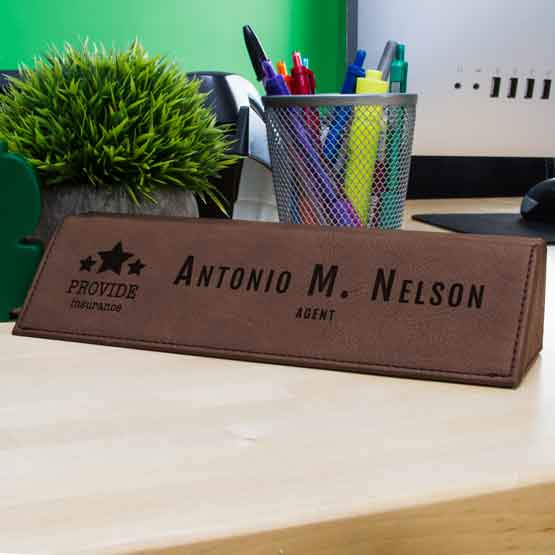 Dark Brown Faux Leather Desk Wedge Engraved With Logo And Employee Details On Office Desk With Computer And Small Plant