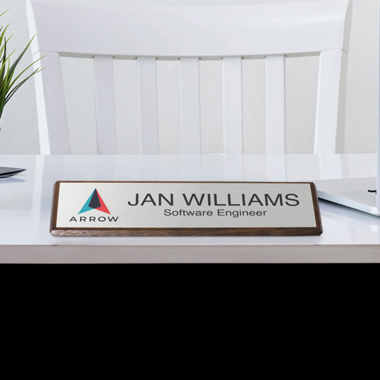 Walnut Desk Wedge With Silver Aluminum Plate Printed With Logo And Employee Details On White Desk With Laptop And Plant