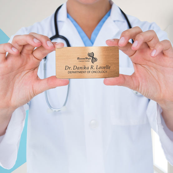 Doctor Holding Custom Bronze Medical Name Tag With Cancer Center Logo And Dr. Lovelle Name. 