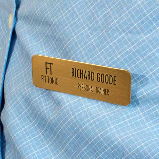 Custom Engraved Brass Metal Name Plate With Logo Attached To Blue Dress Shirt.