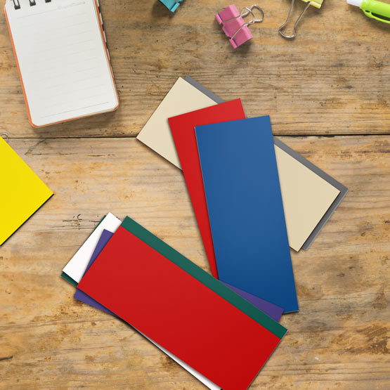 Set Of Ten Blank Plastic Tags With Different Colors Sitting On Wood Work Desk With Laptop And Small Notepad And Clips