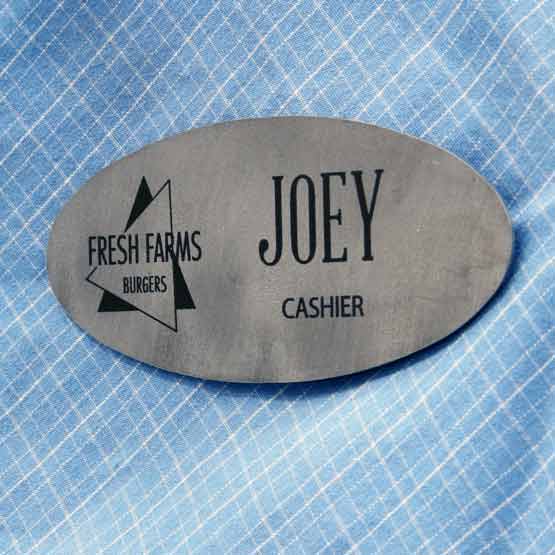 Titanium Oval Magnetic Name Badge Laser Fused With Logo And Name And Cashier Text Fastened To Blue Shirt