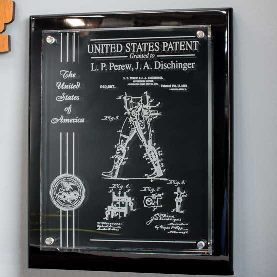 Floating Glass Plaque With A Black Board And Frosted Engravings Of Patent Details And Ribbon And USPTO Seal On Office Wall