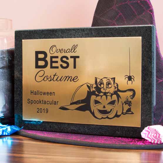 Custom Bronze Award Plaque For Best Halloween Costume With Cute Cat Artwork And Granite Board On Table With Witch Hat