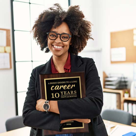 Happy Woman In Office Holding A Custom Metal Plaque Laser Engraved With Appreciation Message For Retirement