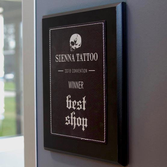 Custom Plaque With Black Faux Leather Plate Featuring Logo And Best Shop Message Mounted On Wall Beside Office Window