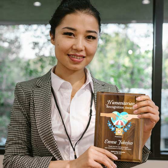 Businesswoman In Office Holding Solid Walnut Plaque Award For Humanitarian Recognition With Organization Logo And Message
