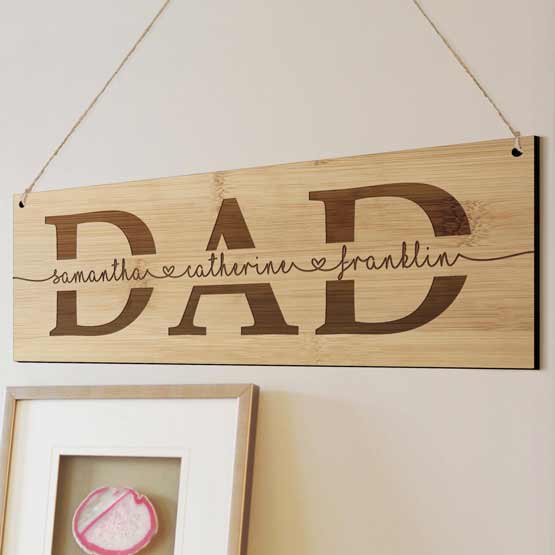 Rectangle Bamboo Sign Engraved With Cursive Kids Names Inside Dad Text Hanging On Living Room Wall Via Holes And Twine