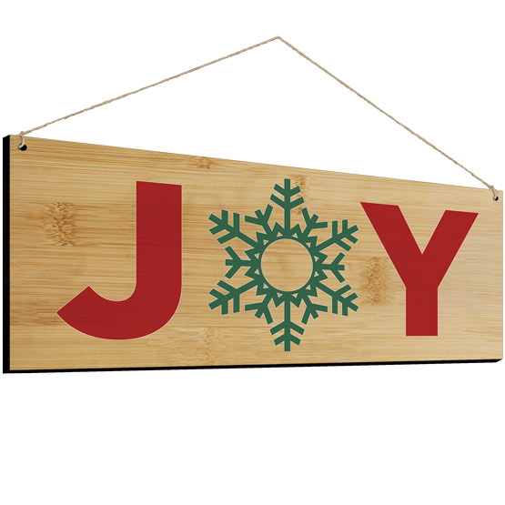 Full Color Bamboo Sign Printed With Snowflake Artwork Inside The Word Joy And Hanging Via Twine Against White Background