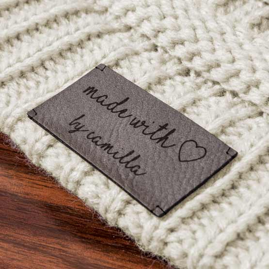 Gray And Black Faux Leather Engraved With Made With Love By Camila Message Featuring Heart Art Fastened To White Quilt