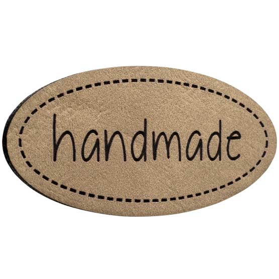 Light Brown And Black Faux Leather Label Engraved With Handmade Text And Stitching Pattern Art Against White Background