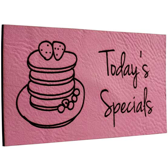 Pink And Black Faux Leather Label Engraved With Cake Artwork And Today’s Specials Message Against White Background