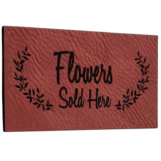 Rose And Black Faux Leather Label Engraved With Wheat Artwork And Flowers Sold Here Message Against White Background