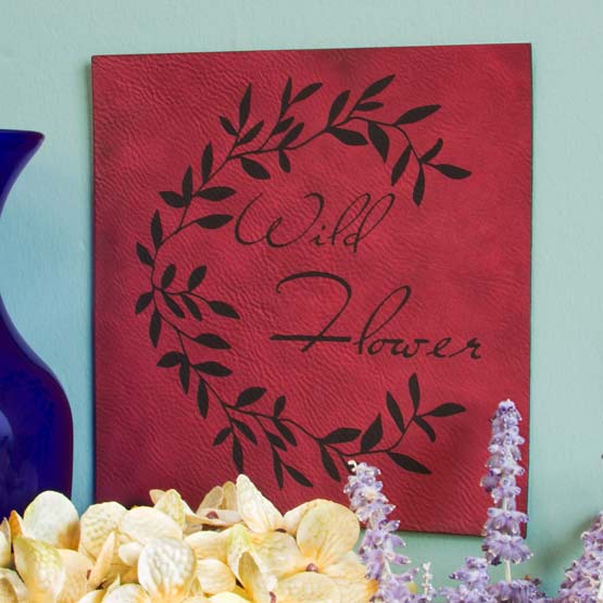 Custom Rose And Black Faux Leather Sign Engraved With Plant Art And Wild Flower Text On Wall Above Flowers And Vase
