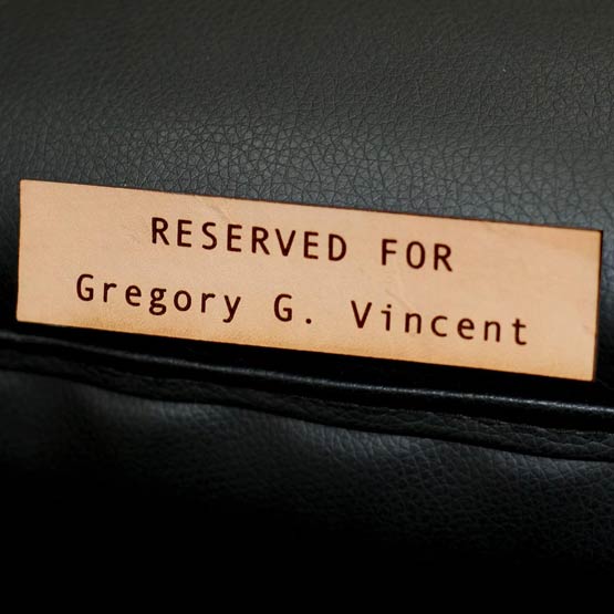 Custom Rectangle Leather Label Laser Engraved With Reserved For Gregory Vincent Message Fastened To Black Chair