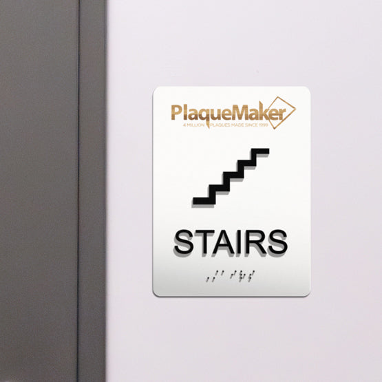 ADA Stairs door signs with tactile lettering and Grade 2 braille hanging by a door.