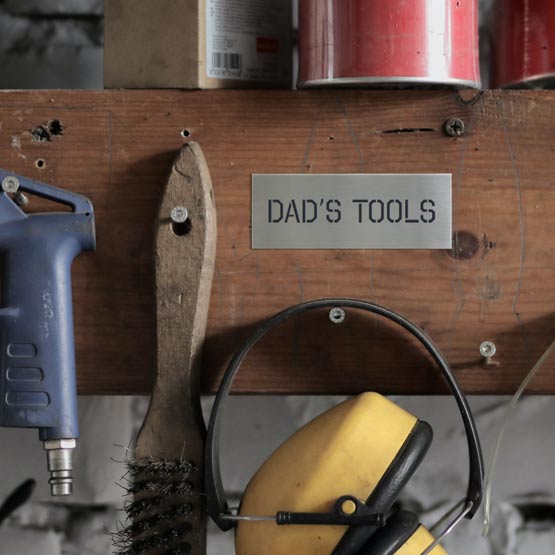 Custom Stainless Steel Label Laser Fused With Dad’s Tools Text Mounted Onto Wood Panel Beside Tools Hanging From Nails