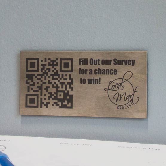 Titanium QR Tag Laser Fused With QR Code And Fill Out Our Survey Message And Grocery Store Logo Mounted On Wall