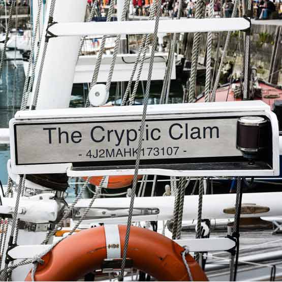 Titanium Sign Laser Fused With The Cryptic Clam Text And ID Number Mounted Onto Small Boat Docked Near Other Boats